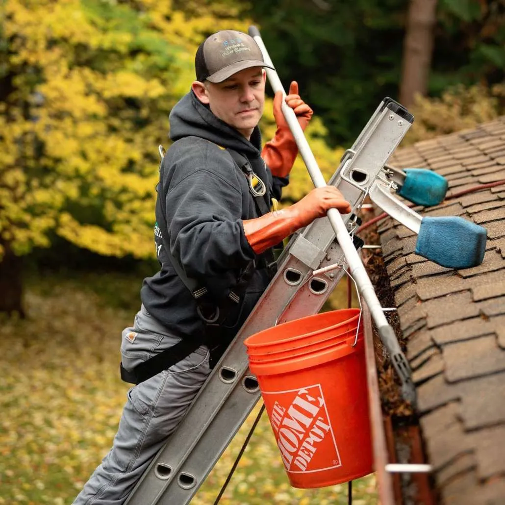 Technician cleaning house gutters